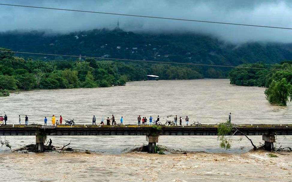 Eine Brücke führt über einen reißenden Strom. 