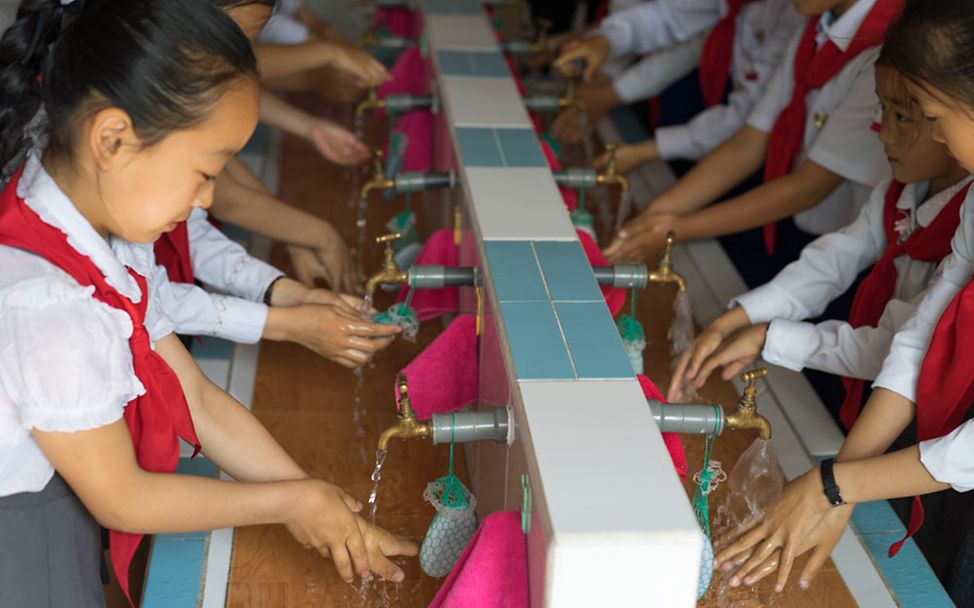 Sauberes Wasser für Nordkorea: Kindergarten-Kinder waschen sich an einem langen Waschbecken mit vielen Anschlüssen die Hände.