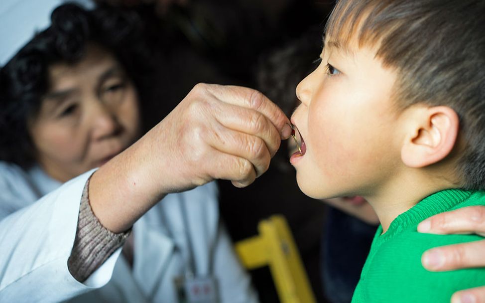 Drohende Hungersnot in Nordkorea: Eine Gesundheitshelferin tropft einem Jungen ein Medikament in den Mund.