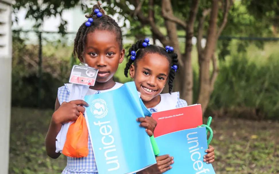 Mädchen auf der Insel Antigua mit UNICEF-Schulheften | © UNICEF/Moreno Gonza Last Minute Geschenke: Zwei Mädchen mit UNICEF-Schulmaterial