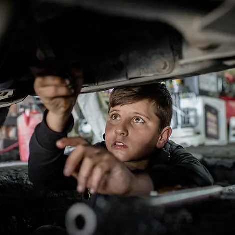 Der 14-jährige Mohammed repariert ein Auto. | © UNICEF/Yar Irak: Junge arbeitet in einer Autowerkstatt.