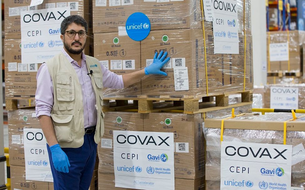 COVAX: UNICEF-Mitarbeiter steht in Dubai vor Palletten mit Spritzen für die Corona-Impfungen.