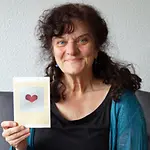 Anne-Marie Kadauke verbindet mit einer UNICEF-Karte eine besondere Liebesgeschichte. | © A.-M. Kadauke Anne-Marie Kadauke hält eine Grußkarte mit einem Herzen in der Hand.