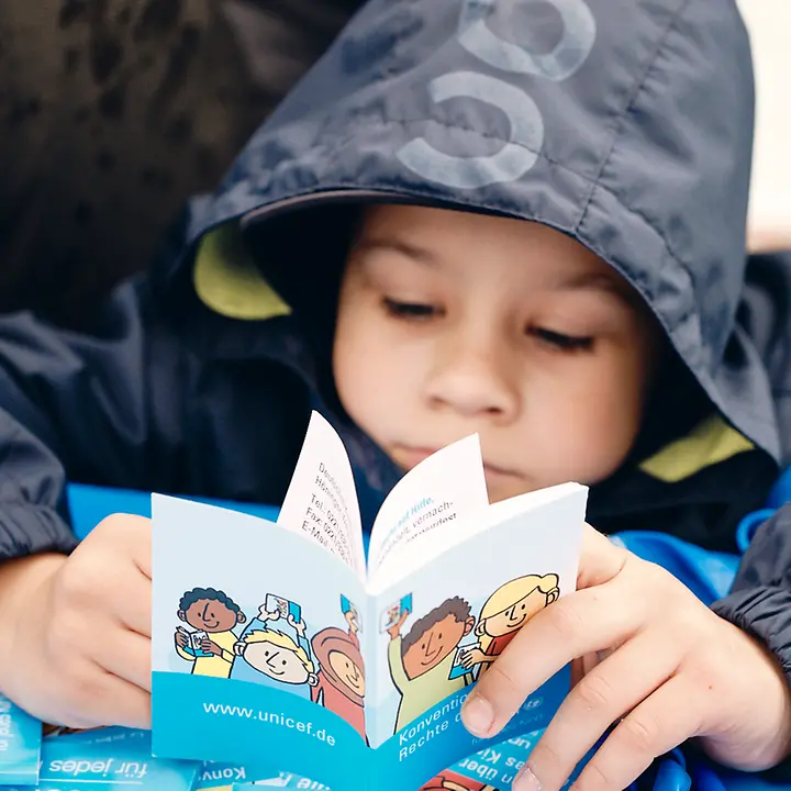 Ein Kind blättert im Kinderrechte-Booklet Ein Kind blättert im Kinderrechte-Booklet