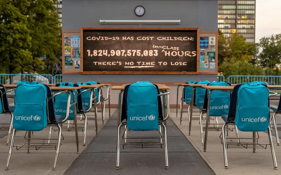 1,8 Billionen verpasste Unterrichtsstunden | © UNICEF/Gary He/UNICEF via Getty Images Installation von UNICEF: Leeres Klassenzimmer und Uhr mit verpassten Unterrichtsstunden.