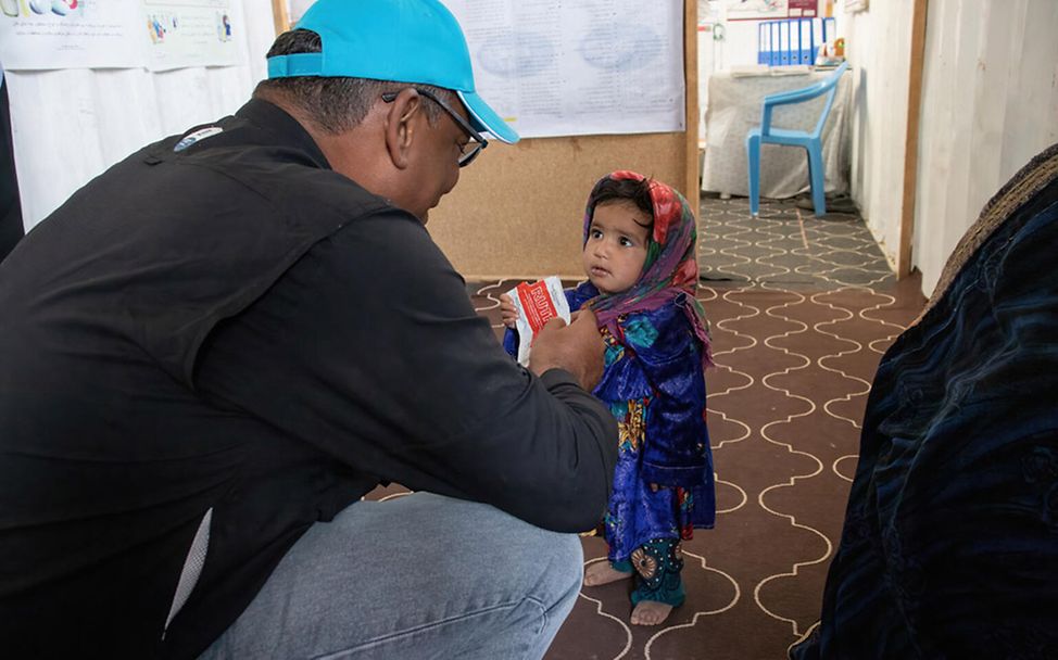 Hunger in Afghanistan: Ein UNICEF-Helfer gibt einem Mädchen Erdnusspaste