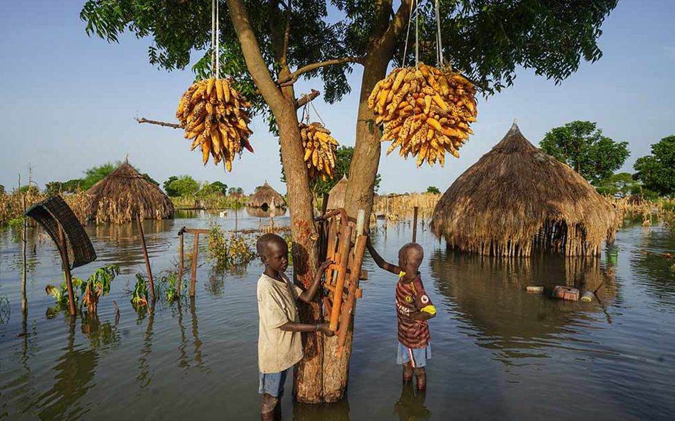 Spenden gegen Flutkatastrophen: Zwei Kinder im Südsudan stehen in ihrem Dorf knietief im Wasser. 