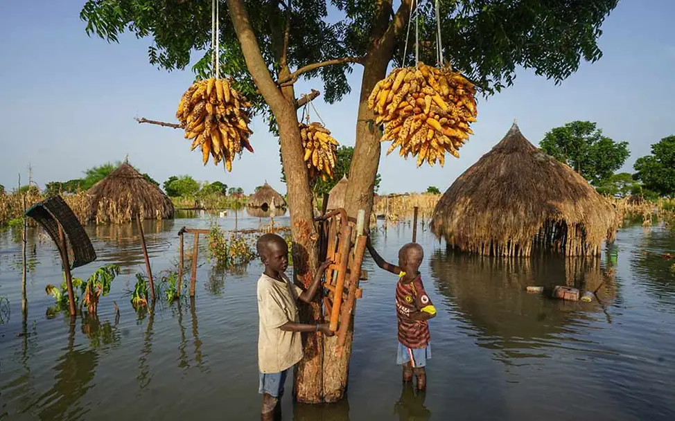 Hilfe für Flutopfer: Zwei Jungen im Südsudan stehen knietief in ihrem überschwemmten Dort. | © UNICEF/Grarup Spenden gegen Flutkatastrophen: Zwei Kinder im Südsudan stehen in ihrem Dorf knietief im Wasser.