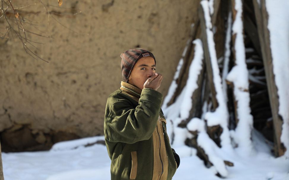 Winter in Afghanistan: Ein Junge steht im Schnee und wärmt seine Hände