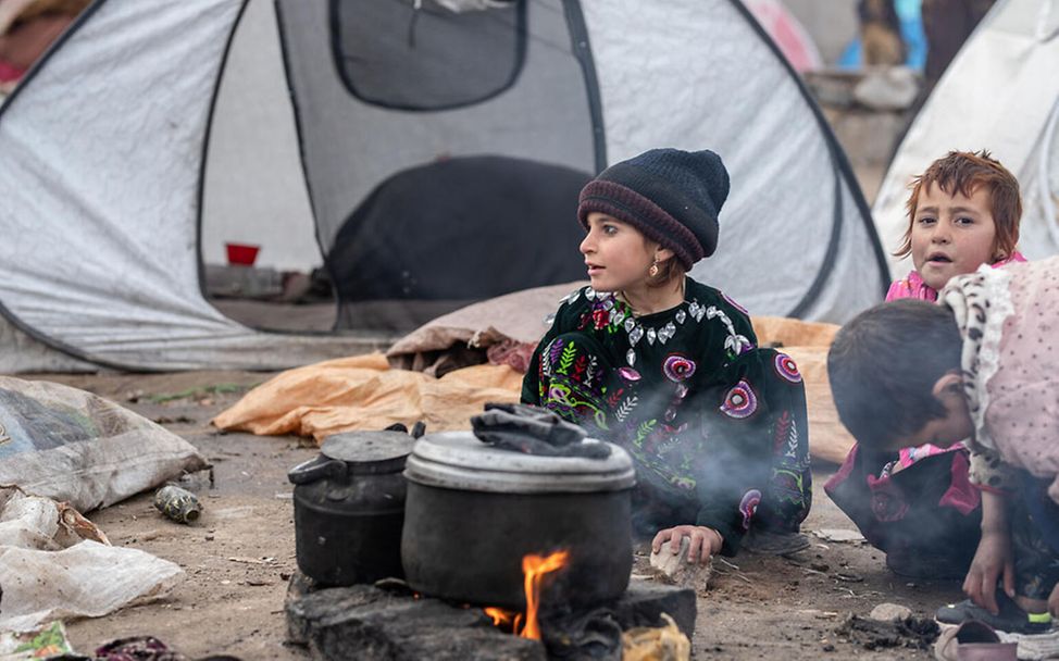 Afghanistan Kinder: Kinder sitzen in einem Flüchtlingscamp um eine Feuerstelle