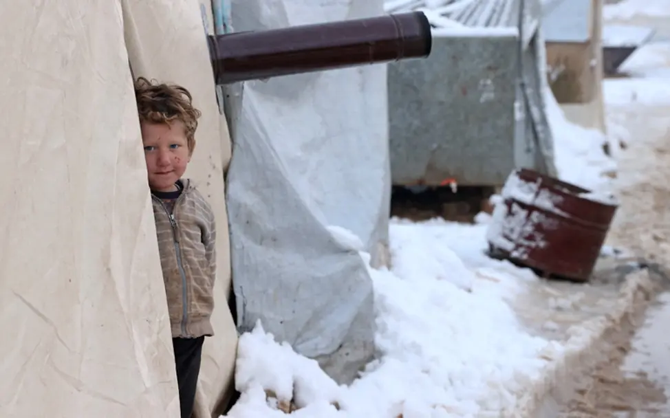 Syrien Winter 2022: Ein Junge steht im Schnee am Eingang eines Zeltes | © OMAR HAJ KADOUR / AFP Syrien Krieg im Winter 2022: Ein Junge steht im Schnee am Eingang eines Zeltes