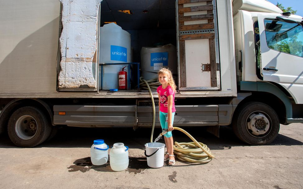 Die achtjährige Dasha aus Pavlopil füllt Eimer mit sauberem Wasser, das von UNICEF bereitgestellt wurde.