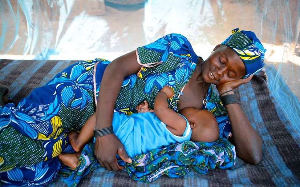 Niger: Eine Mutter stillt ihr Baby unter einem Moskitonetz © UNICEF/Pirozzi