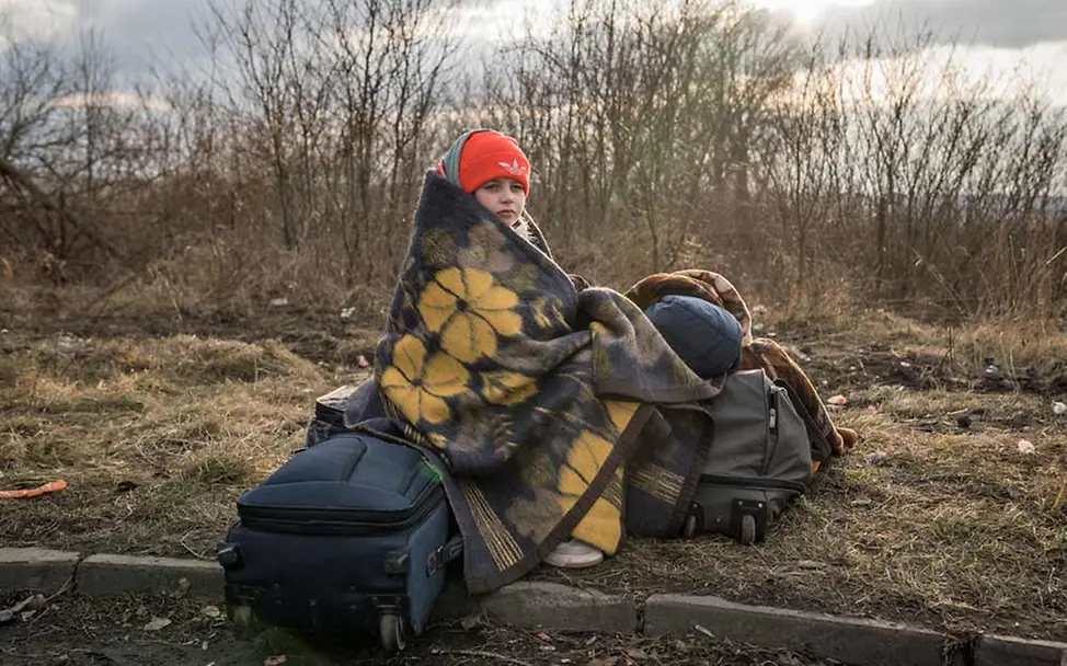 Der Ukraine-Konflikt hat innerhalb weniger Tage Hunderttausende Menschen zu Flüchtlingen gemacht. | © UNICEF/Moldovan Ukraine-Konflikt: Eingehüllt in eine Decke sitzt ein geflüchtetes Mädchen auf Koffern.
