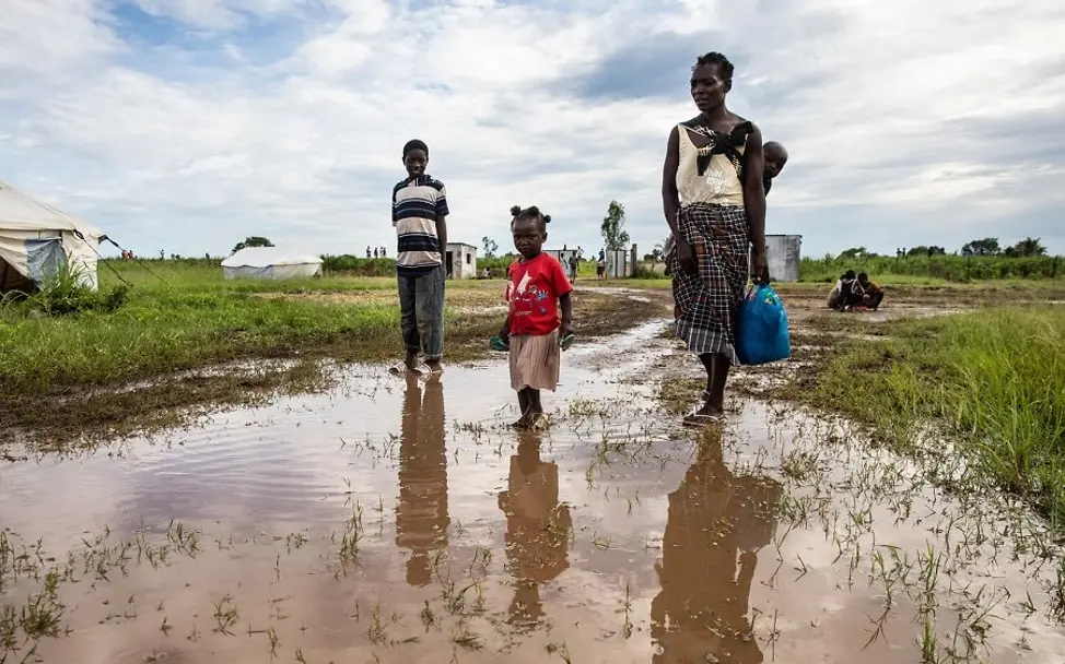 Überschwemmungen iin Mosambik nach dem Sturm Eloise. | © UNICEF/Franco Eine Mutter läuft mit ihrem Kind über ein überschwemmtes Feld.