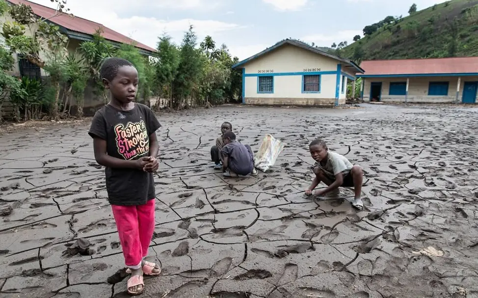 Starke Regenfälle führten 2020 in der Demokratischen Republik Kongo zu Überflutungen.| © UNICEF/Desjardins Kinder stehen auf einem zerstörten Feld.