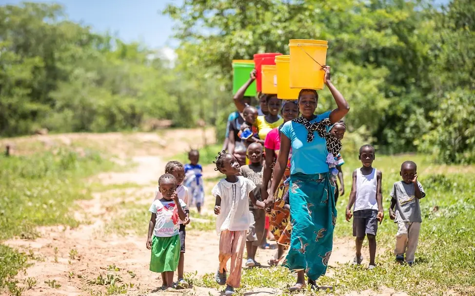 In Sambia gehen Menschen weite Wege um an sauberes Trinkwasser zu kommen. | © UNICEF/UNI308269/Schermbrucker Frauen tragen bunte Eimer auf ihren Köpfen.