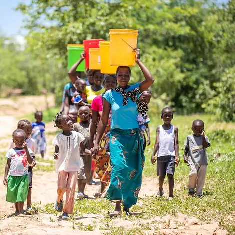 In Sambia gehen Menschen weite Wege um an sauberes Trinkwasser zu kommen. | © UNICEF/UNI308269/Schermbrucker Frauen tragen bunte Eimer auf ihren Köpfen.