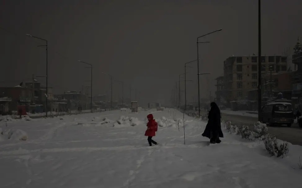 Eine Mutter läuft mit ihrer Tochter durch die verschneiten Straßen von Kabul. | © UNICEF/UNI303821/Modola Eine Mutter läuft mit ihrer Tochter durch die verschneiten Straßen von Kabul.