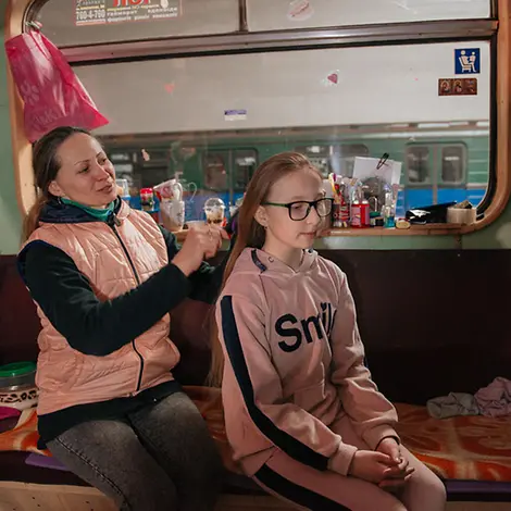 Ukraine-Krieg: Eine Mutter kämmt ihrer Tochter in der U-Bahn von Charkiw die Haare | © UNICEF/Pashkina Ukraine-Krieg: Eine Mutter kämmt ihrer Tochter in der U-Bahn von Charkiw die Haare