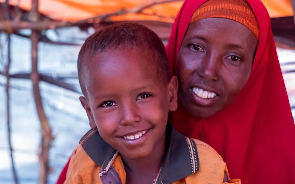 Somalia: Familien leiden Hunger. | © UNICEF/Rich Der vierjährige Abdirahman sitzt mit seiner Mutter vor einem Zelt in einem Camp für vertriebene Familien