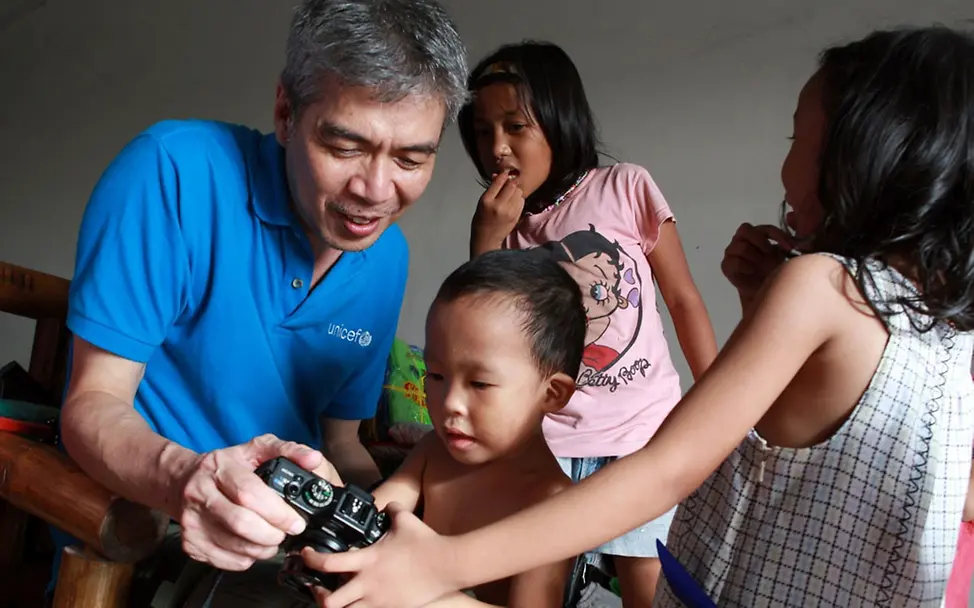 UNICEF-Mitarbeiter Nonoy Fajardo mit Kindern in Tacloban. © UNICEF/Maitem. UNICEF-Mitarbeiter Nonoy Fajardo mit Kindern in Tacloban. © UNICEF/Maitem.