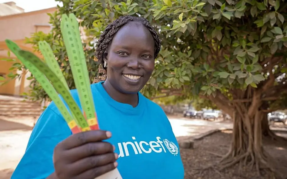 UNICEF-Helferin Mary Achii hält MUAC-Maßbänder in der Hand. | © UNICEF/Naftalin Hungerkrise: Eine UNICEF-Helferin in einem Entwicklungsland hält Maßbänder für Oberarmmessungen bereit.