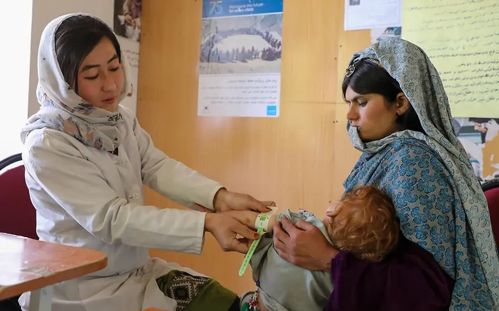 Eine afghanische Ernährungshelferin untersucht ein Kind auf Mangelernährung. | © UNICEF/Fazel Hungerkrise: Eine Ernährungshelferin in Afghanistan untersucht ein Kind auf Mangelernährung.