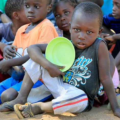 Mosambik: Spenden für Kinder in Not. Junge mit leerem Teller in der Hand