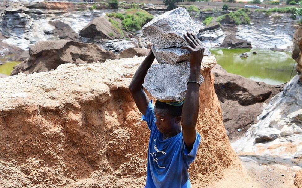 Burkina Faso: Ein Junge transportiert Steinbrocken auf seinem Kopf