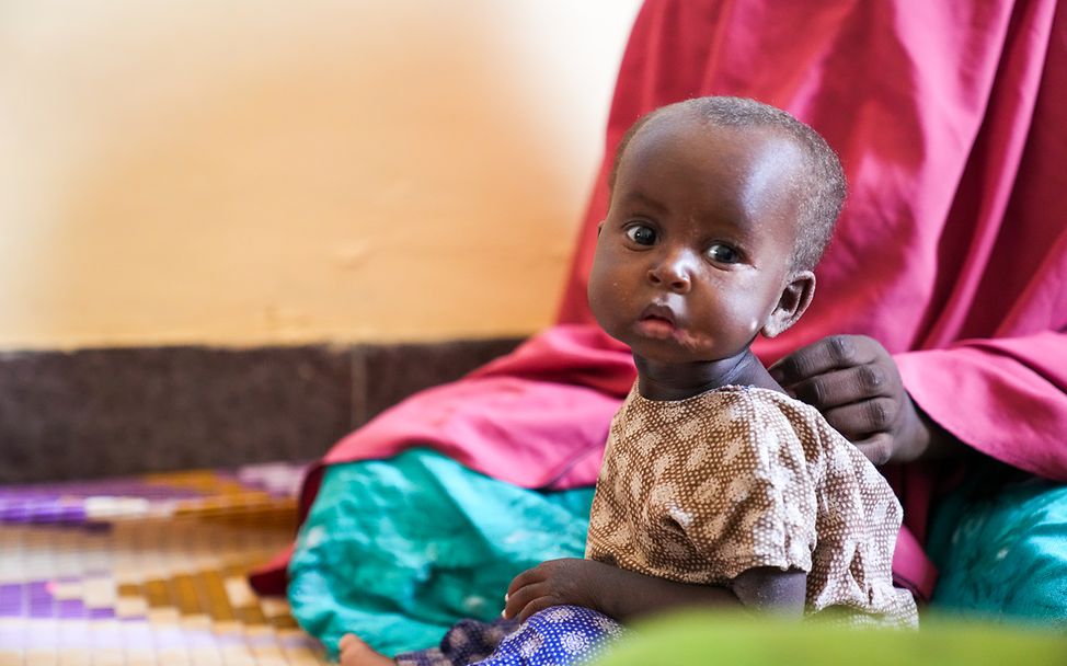 Somalia: Ein kleines Mädchen sitzt auf dem Boden und schaut in die Kamera.