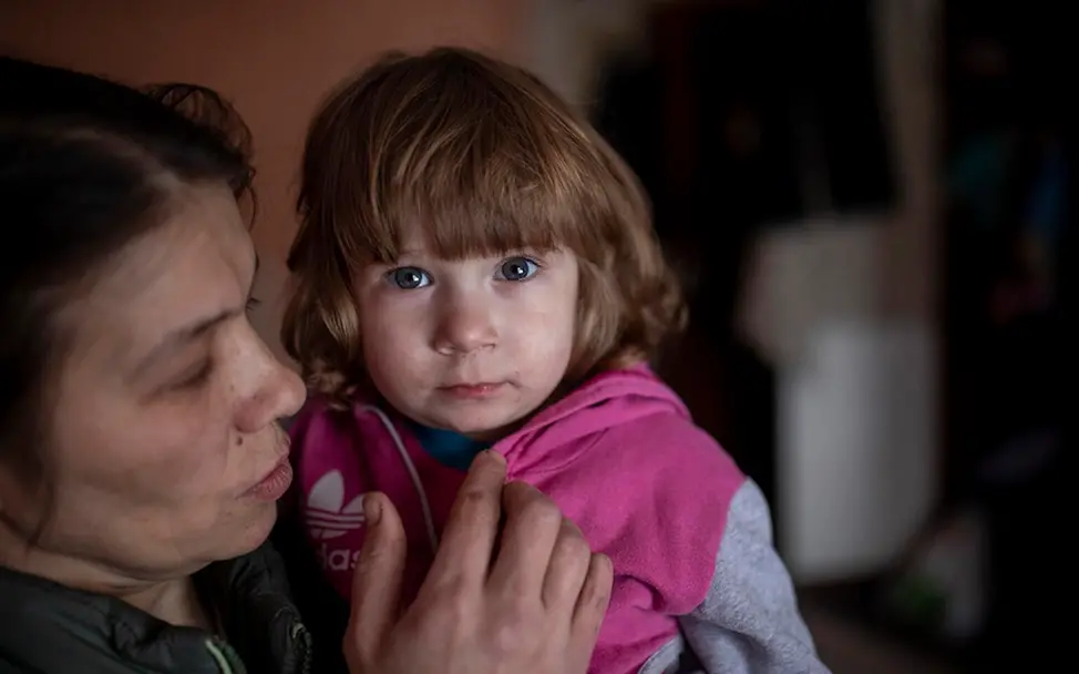 Vier Millionen Kinder in Armut I UNICEF/Filippov Ukraine: Ein Mädchen auf dem Arm ihrer Mutter schaut in die Kamera.