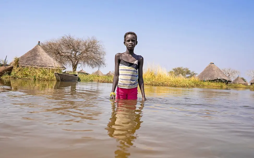 UNICEF zur Klimakonferenz COP27 I UNICEF//Naftalin Südsudan: Ein Junge steht knietief im Wasser und schaut frontal in die Kamera.