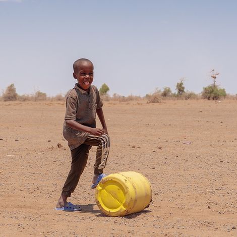 Dürre in Kenia: Kinder spielt mit Plastikkanister in der Sandwüste.