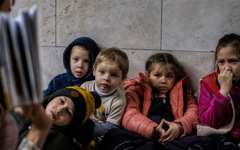 Eine Lehrerin liest einer Gruppe von Mädchen und Jungen in einem Souterrain der Hauptstadt Kiew Geschichten vor.