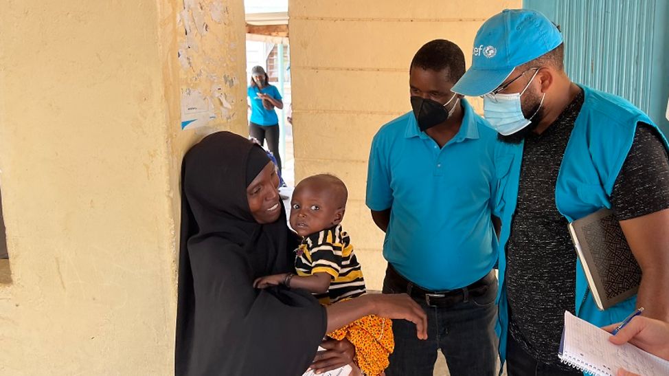 Kenia: UNICEF-Helfer*innen unterhalten sich mit einer Mutter, de hr Kind auf dem Arm trägt