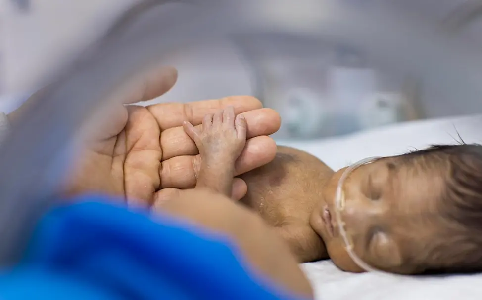 Mutter im Irak hält Hand ihres Frühchens im Brutkasten | © UNICEF/ Njiokiktjien Kindersterblichkeit: Viele Babys sterben bei Geburt