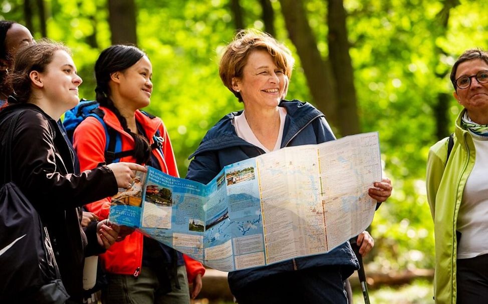 Eine Gruppe von Wandernden hält eine Wanderkarte in der Hand.