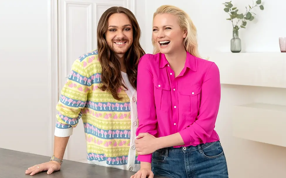 Franziska Knuppe und Riccardo Simonetti werben für neue UNICEF-Grußkarten zum Selbstgestalten I UNICEF/Lindenthal-Lazhar Franziska Knuppe und Riccardo Simonetti stehen vor einem Tisch nebeneinander und lächeln.