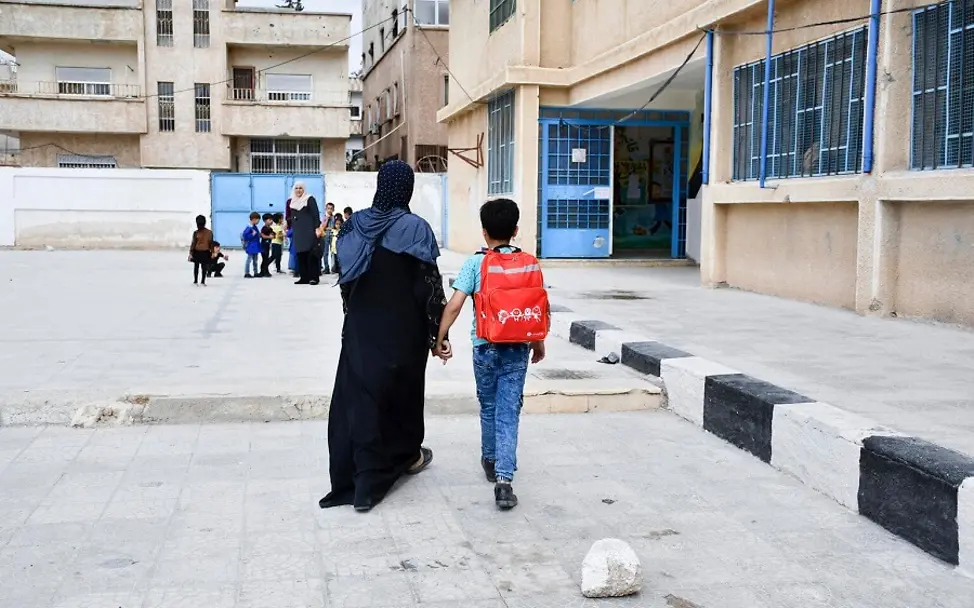 Ahmad überquert mit seiner Mutter den Schulhof. | © UNICEF/Shahan Syrien: Ahmad geht mit seiner Mutter Hand in Hand über den Schulhof.