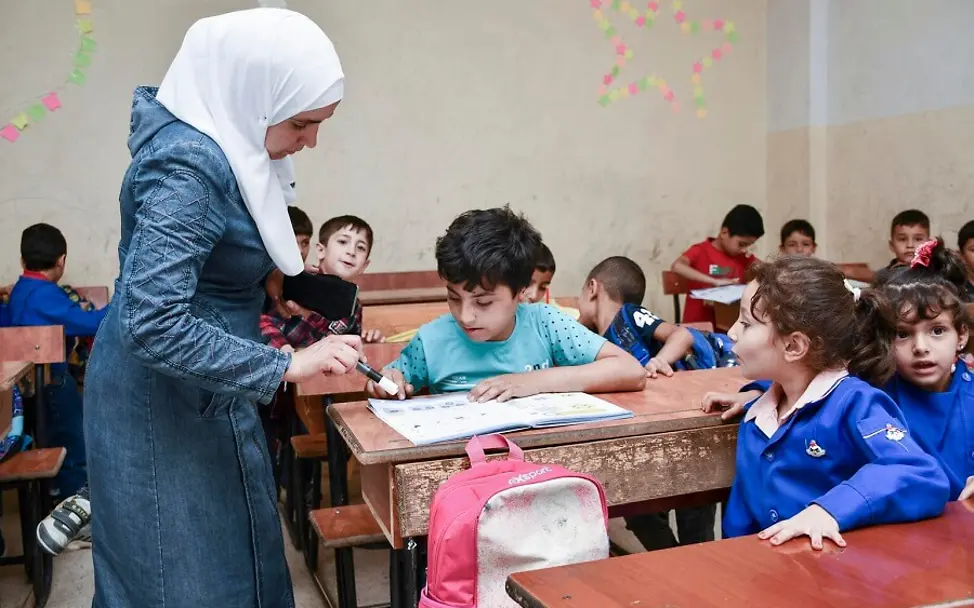 Ahmad strengt sich im Unterricht an. | © UNICEF/Shahan Syrien: Ahmad sitzt im Matheunterricht und schaut sich mit seiner Lehrerin sein Aufgabenheft an.