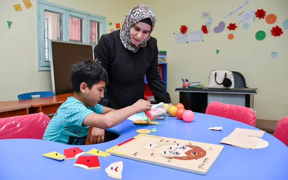 Ahmad übt im Förderunterricht. |© UNICEF/Shahan Syrien: Ahmad und seine Lehrerin sitzen vor einem Lernspiel.