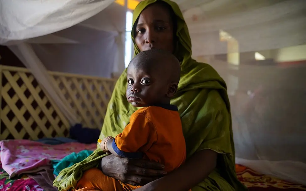 Sudan: Mehr als eine Million Kinder vertrieben I UNICEF/Zakaria Sudan: Ein Kind sitzt auf dem Schoß seiner Mutter und beide schauen in die Kamera
