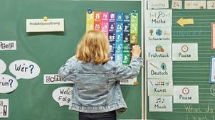 Kinderrechteschulen: Ein Mädchen steht an der Tafel und betrachtet ein Bild zu Kinderrechten