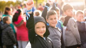 Kinderrechteschulen: Ein Junge streckt seine Faust in die Höhe beim Schülerlauf der Schule am Mohnweg.