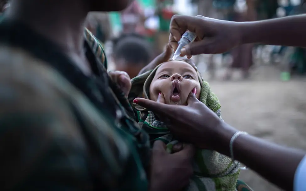 Kinderimpfungen nehmen nach Rückschlägen während der Covid-19-Pandemie wieder zu I UNICEF/Ayene Äthiopien: Ein Kind auf dem Arm seiner Mutter erhält eine Schluckimpfung.