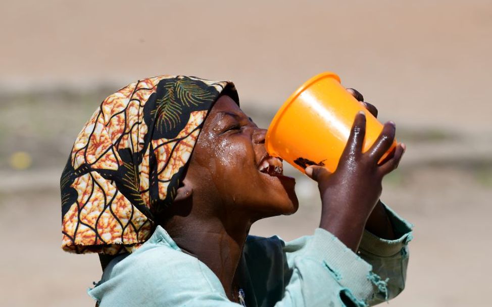 Hitze Kinder: Ein Mädchen trinkt Wasser aus einem großen Becher