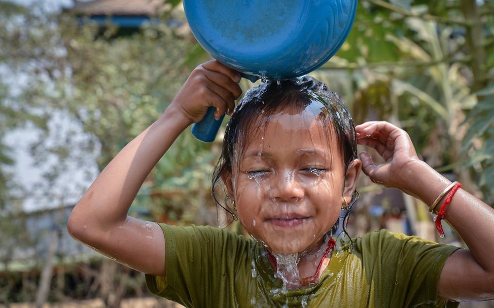 Hitze KInder: Junge kühlt seinen Kopf mit Wasser.