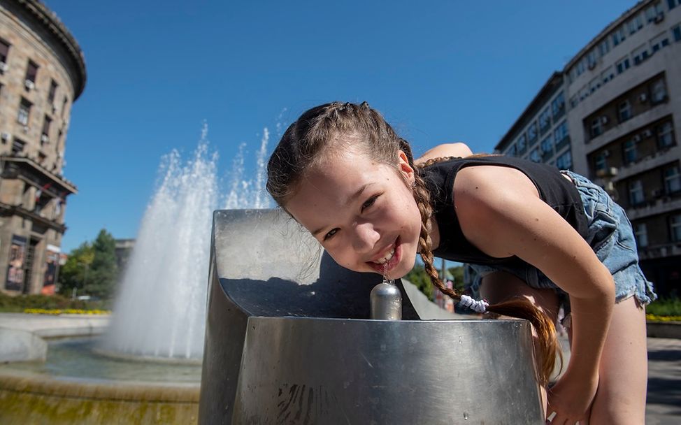 Hitze Kinder: Mädchen trinkt an Trinkwasserbrunnen in Serbien.