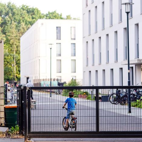 Ein Junge fährt auf dem Gelände einer Unterkunft für Geflüchtete Fahrrad.